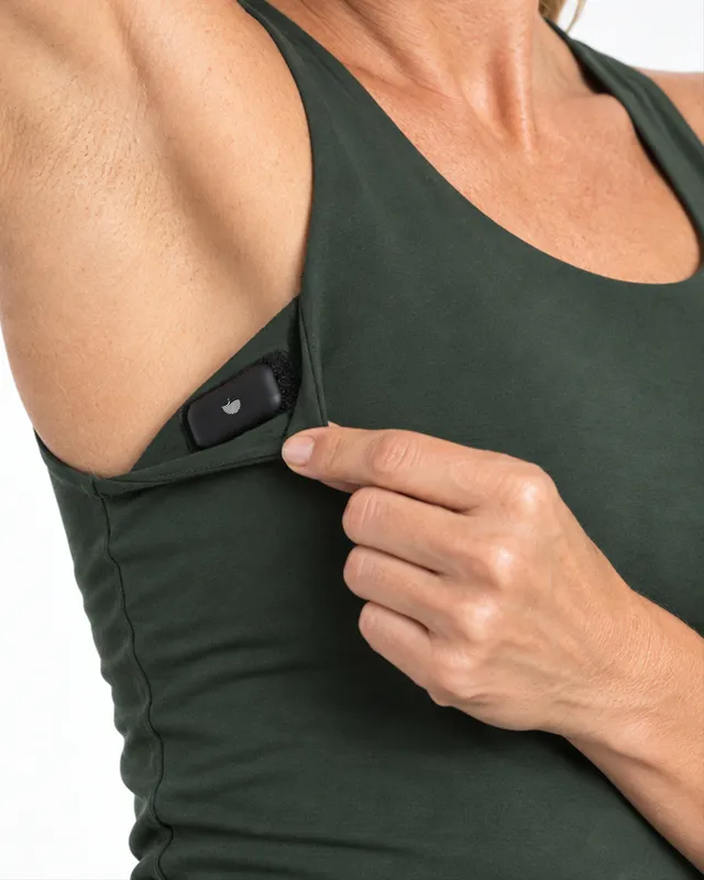 Close-up of the discreet side pocket on the Aleena tank, holding a wearable device