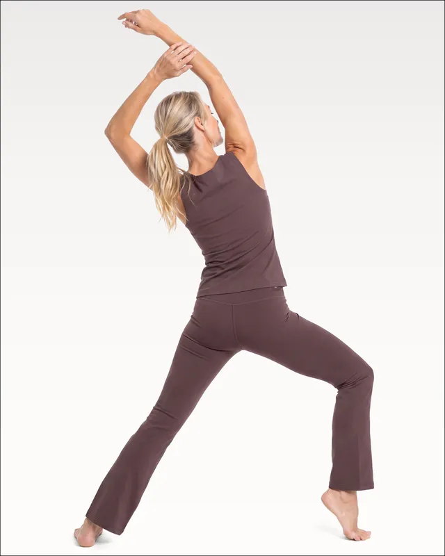 Woman in a reaching lunge wearing the Ardra legging in raisin with the Aleena tank