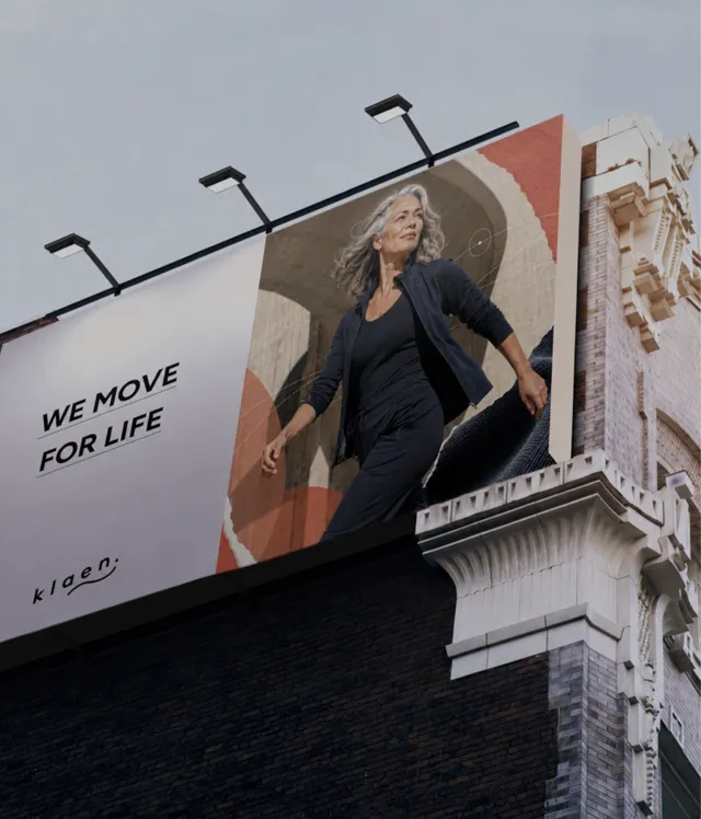 Klaen billboard reading We Move For Life, showing a grey-haired woman striding out in black Klaen Movement Wear